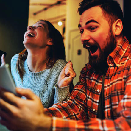 Excited male and female hipsters rejoice in winning an internet lottery made bets on website on modern smartphone.Happy couple in love celebrating victory in online competitions enjoying success