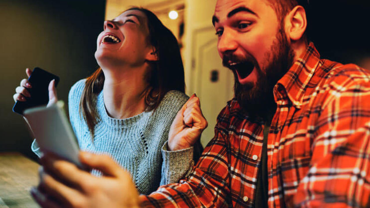 Excited male and female hipsters rejoice in winning an internet lottery made bets on website on modern smartphone.Happy couple in love celebrating victory in online competitions enjoying success