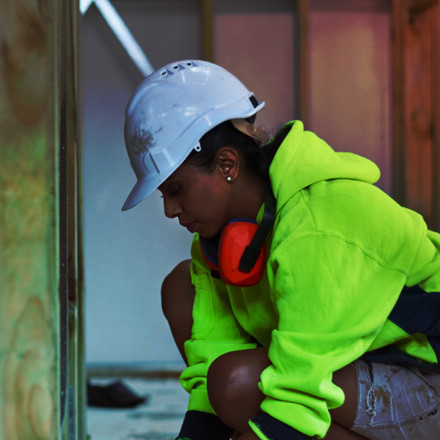 Female worker using tape measure at site.