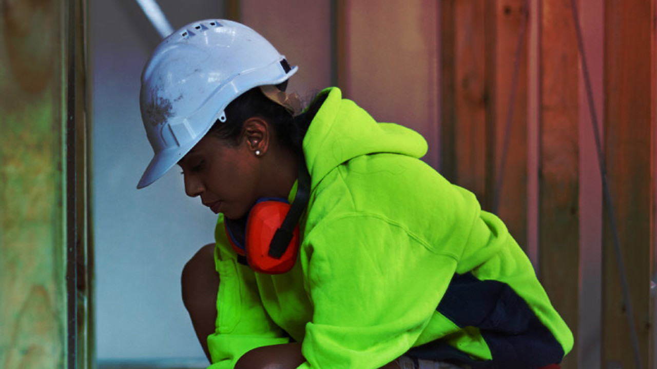 Female worker using tape measure at site.