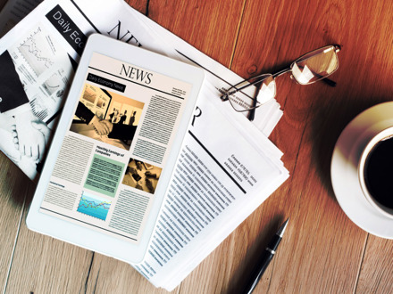 Newspaper with tablet on wooden table