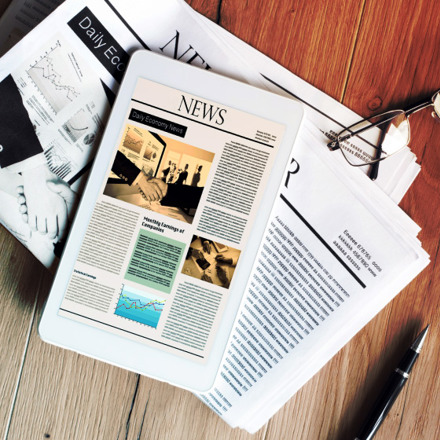 Newspaper with tablet on wooden table