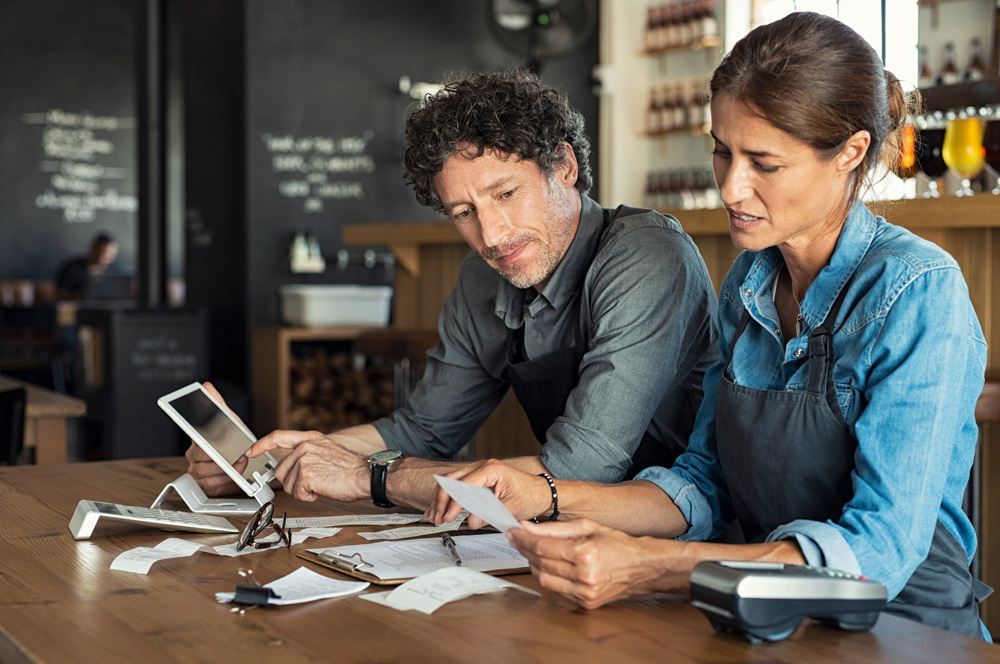 Small business owners sitting at a table and pondering over financials.