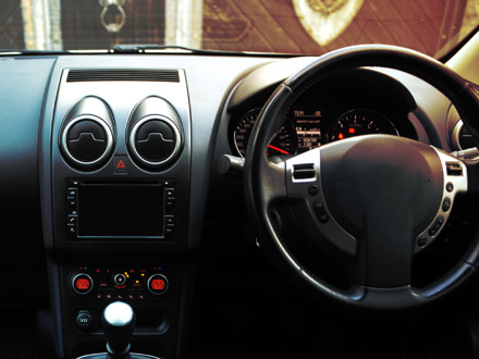 Modern luxury prestige car interior, dashboard, steering wheel. Black perforated leather interior.