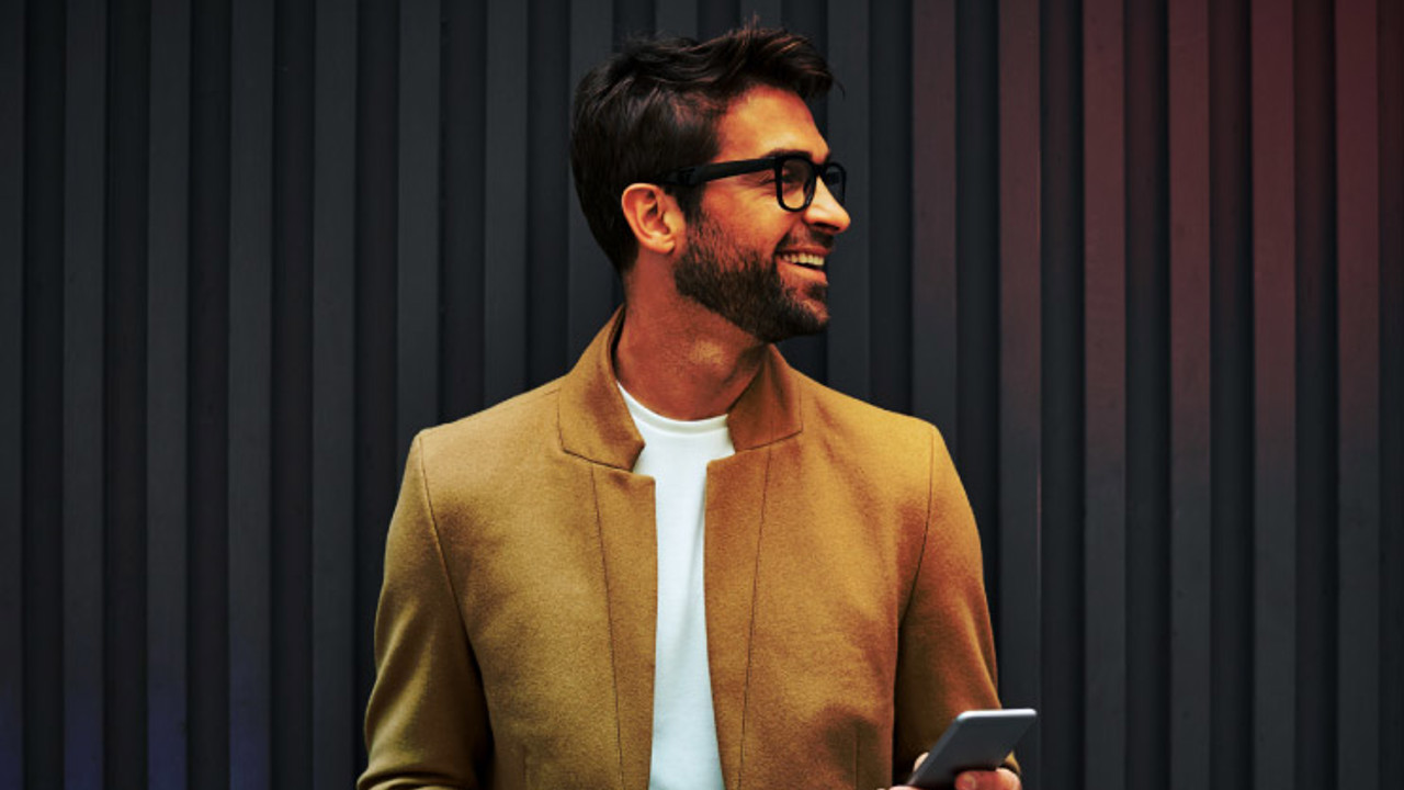 Smiling businessman with smart phone and cup.