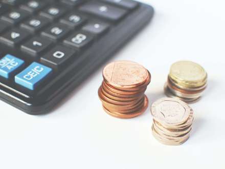 Calculator and three stacks of coins. 