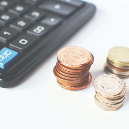 Calculator and three stacks of coins. 