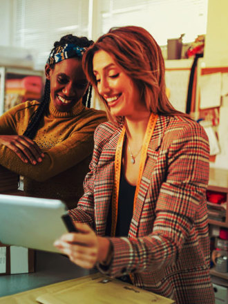 Two women looking at their ERP system on a laptop while in their store.  