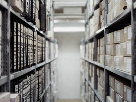 Walkway between shelves holding boxes and files. 