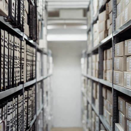 Walkway between shelves holding boxes and files. 