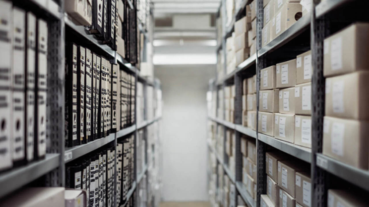 Walkway between shelves holding boxes and files. 