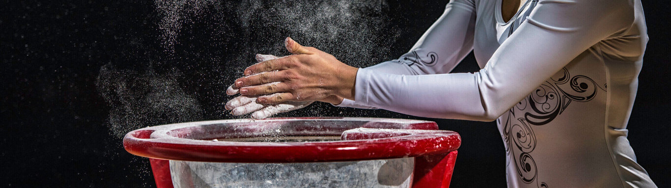 Female gymnast chalking her hands.