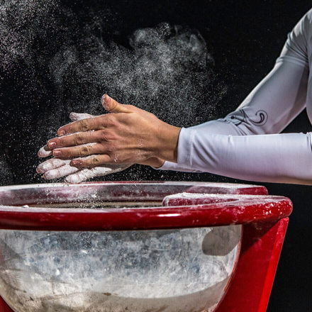 Female gymnast chalking her hands.