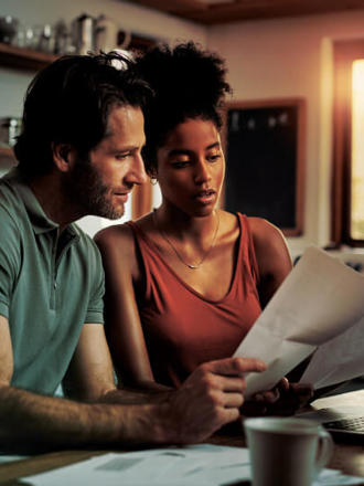 Cropped shot of an affectionate young couple going through paperwork while doing their budget at home.