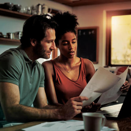 Cropped shot of an affectionate young couple going through paperwork while doing their budget at home.