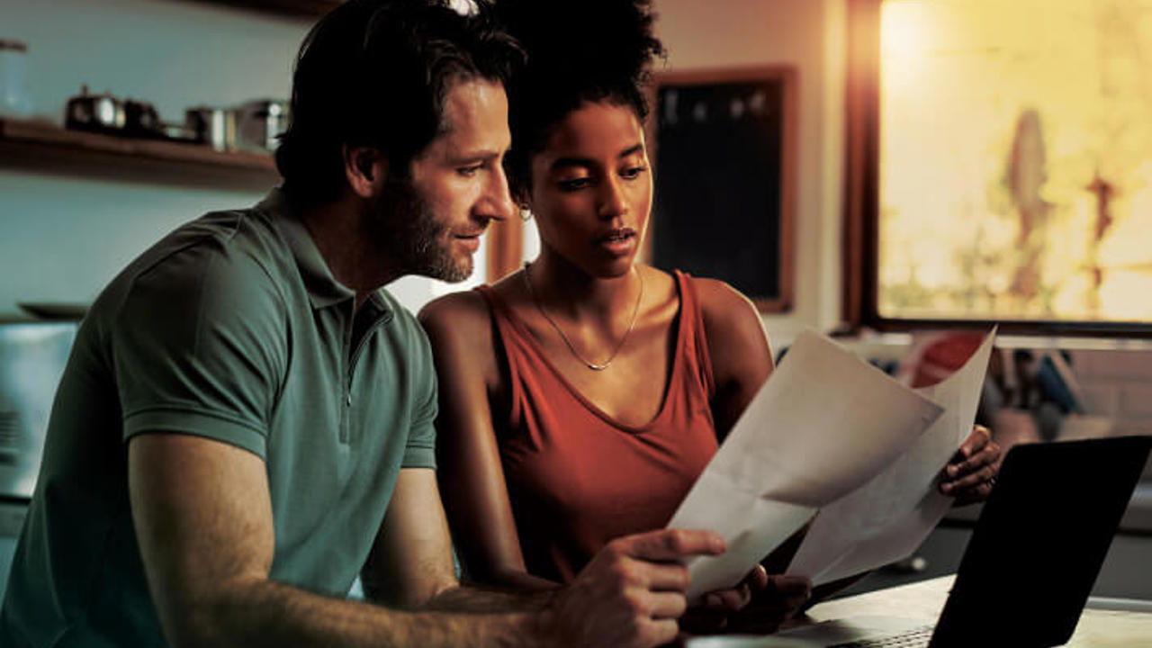 Cropped shot of an affectionate young couple going through paperwork while doing their budget at home.