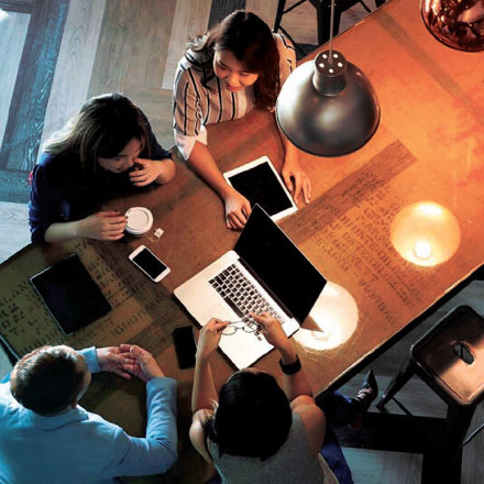 Staff sitting around a table working on their business solutions.