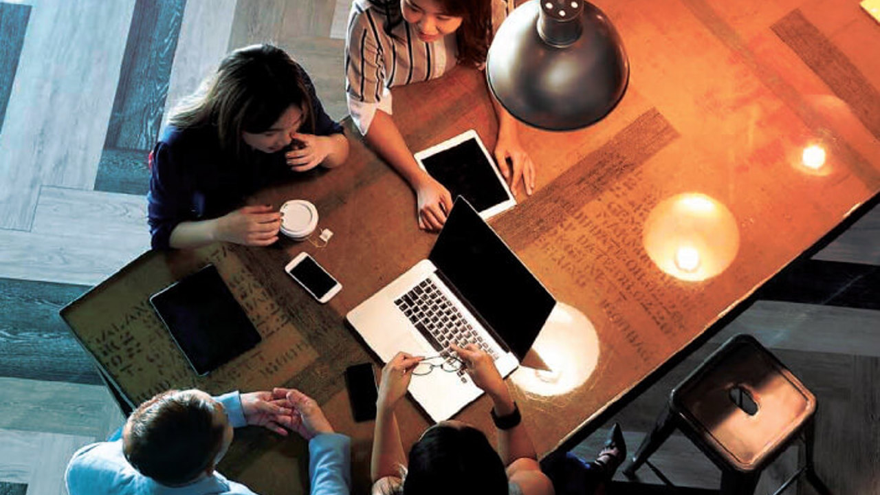 Staff sitting around a table working on their business solutions.