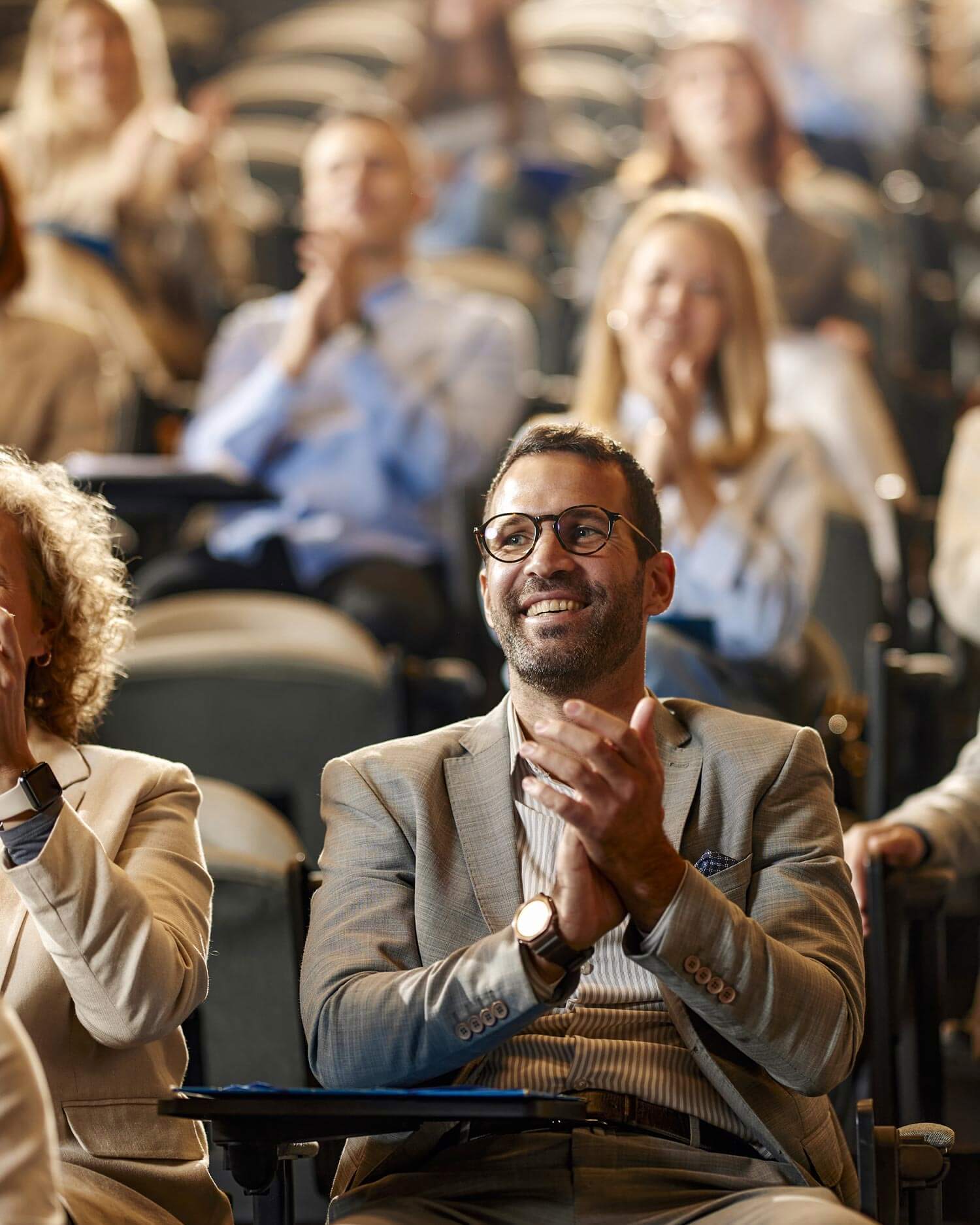 Happy mid adult businessman applauding on successful education event in convention center.