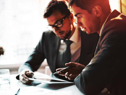 Two business men discussing something important on a tablet.