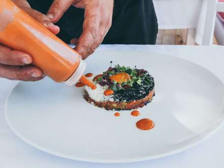 Chef adding sauce to his creation.