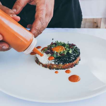 Chef adding sauce to his creation.