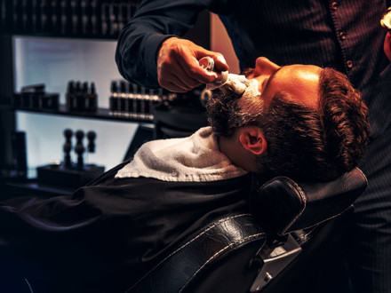 Barber applies shaving foam to a man's face in a saloon.