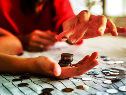 Woman's hands counting coins on a table.