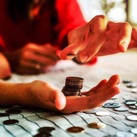 Woman's hands counting coins on a table.