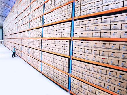 Man in a warehouse in front of a wall of boxes.