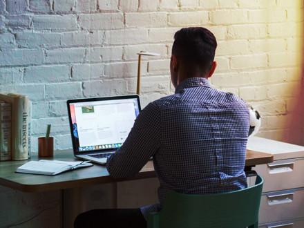 Man sitting down and using his laptop. Working from home. 