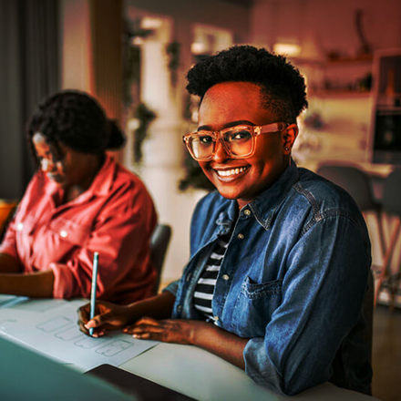 Women working together at home, sitting at same table.