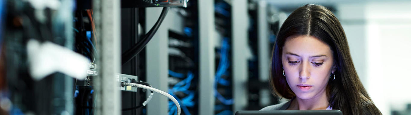 Woman looking at her device while standing next to a data centre. 