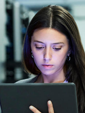 Woman looking at her device while standing next to a data centre. 