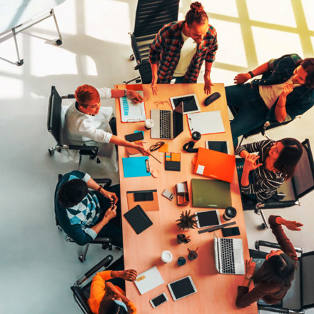 Multi-ethnic diverse group of business coworkers in team meeting discussion, top view modern office with copy space. Partnership professional teamwork, startup company, or project brainstorm concept.