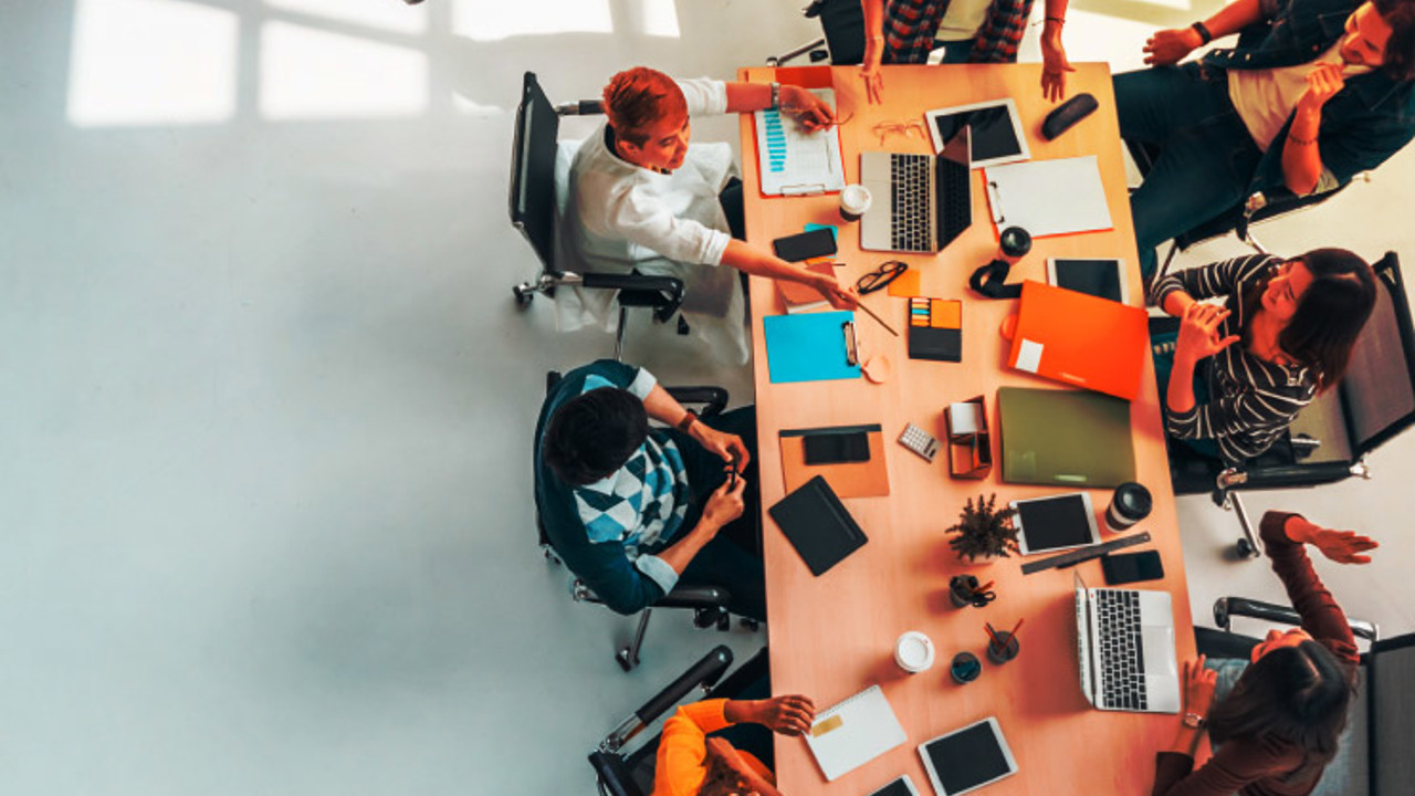 Multi-ethnic diverse group of business coworkers in team meeting discussion, top view modern office with copy space. Partnership professional teamwork, startup company, or project brainstorm concept.