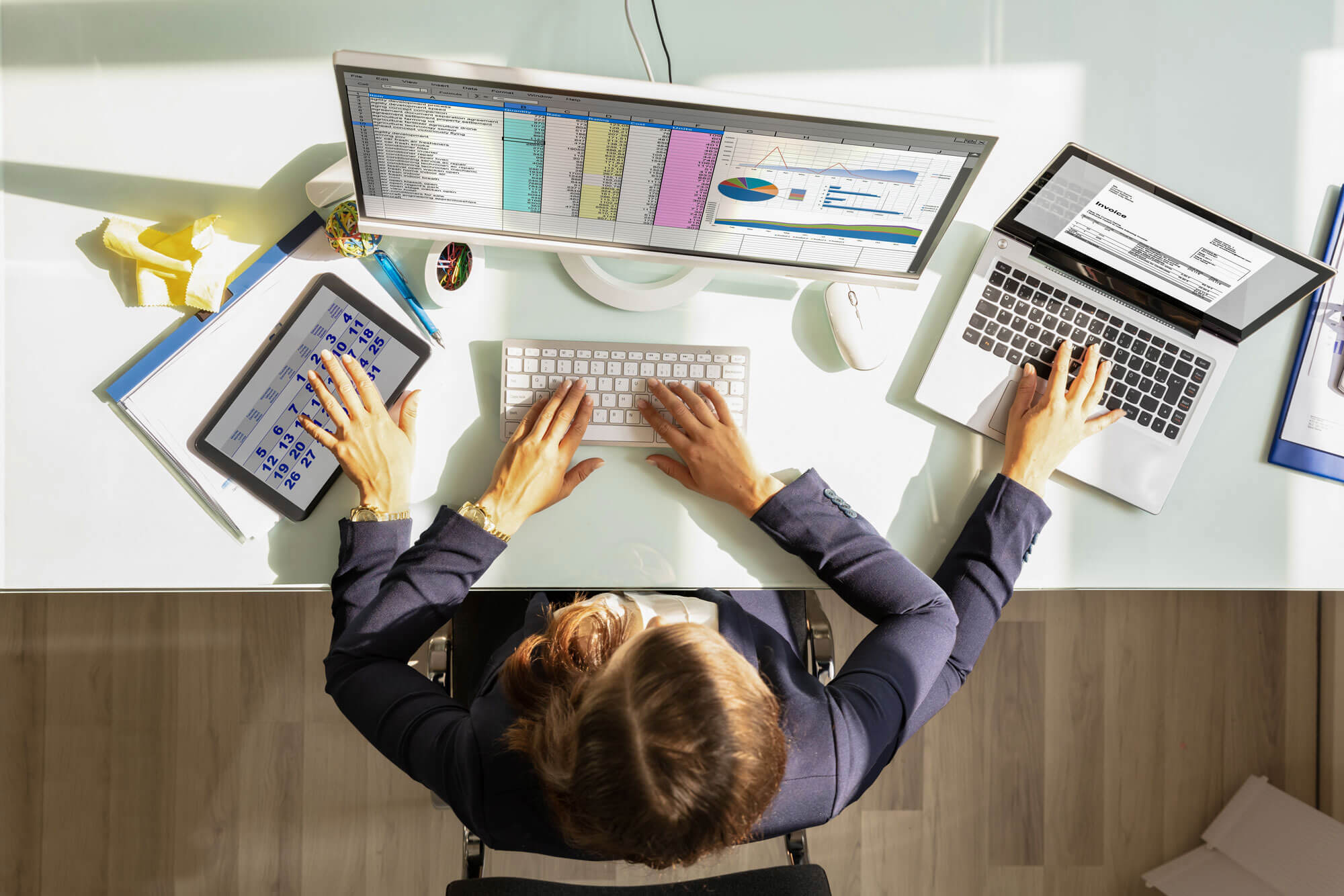 Overhead View Of A Businesswoman Doing Multitasking Work On Electronic Devices.