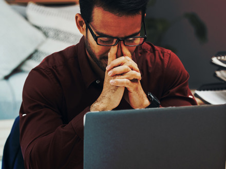 A business professional looks frustrated at his accounting software on his laptop computer