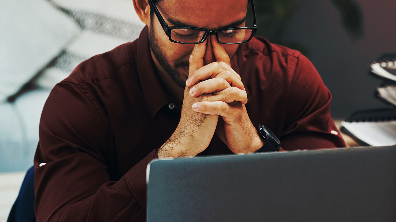 A business professional looks frustrated at his accounting software on his laptop computer