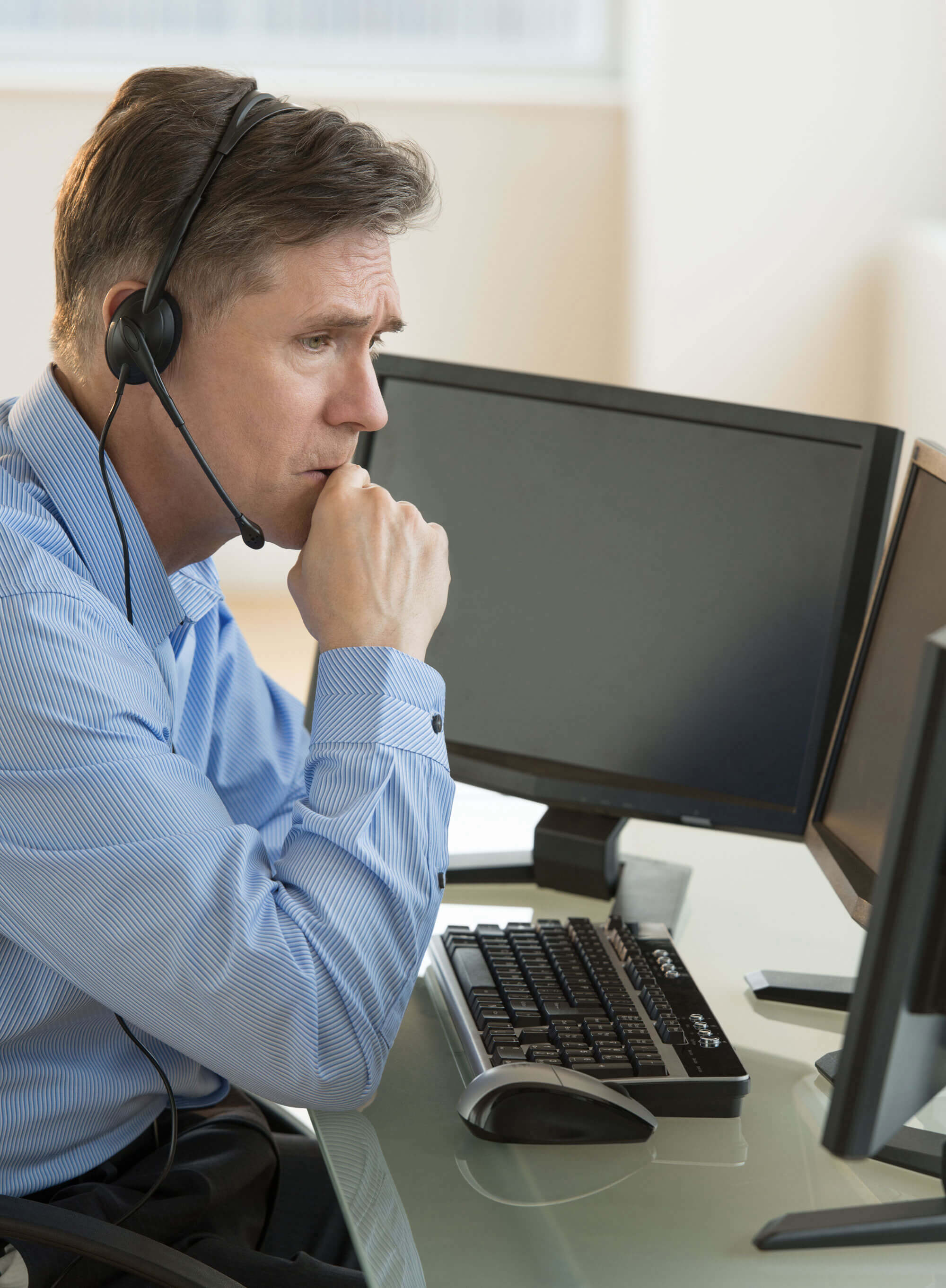 Male Customer Service Representative Looking At Computer Monitor.