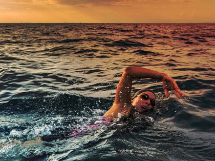 Female open water swimmer swimming forward crawl in sea.