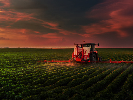 Tractor spraying pesticides on soy field with sprayer at spring.