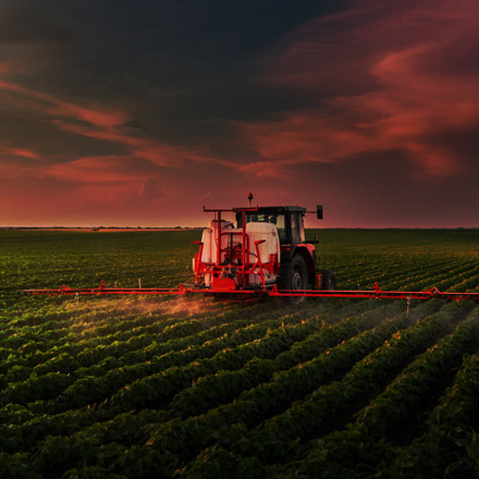 Tractor spraying pesticides on soy field with sprayer at spring.