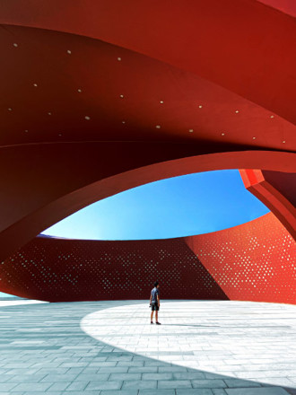 A person standing in a red curved abstract architectural space, 3D rendering.