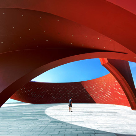 A person standing in a red curved abstract architectural space, 3D rendering.