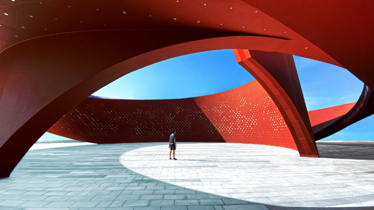 A person standing in a red curved abstract architectural space, 3D rendering.