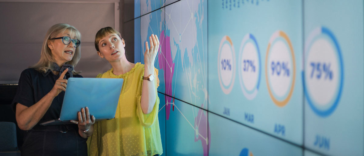 Businesswomen Discussing Ideas Against an Information Wall