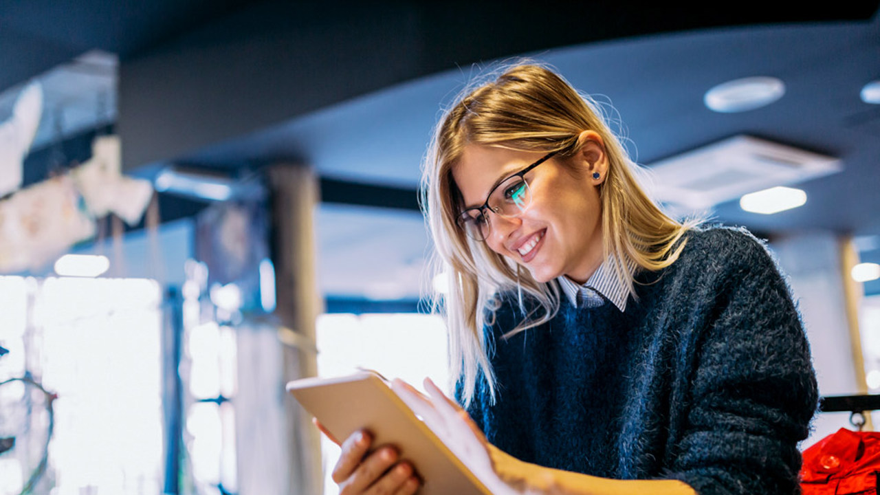 Smiling blond woman reading something on her tablet. 