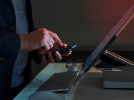 Hand of a man calculating in front of a Microsoft Surface Studio.