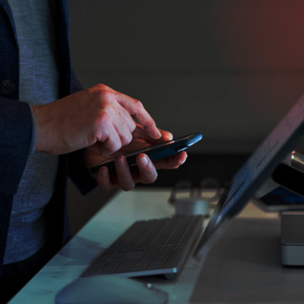 Hand of a man calculating in front of a Microsoft Surface Studio.